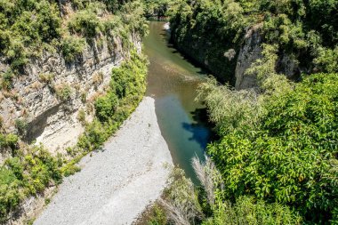 Rangitikei Nehri 'nin turkuaz suyu Yeni Zelanda' nın Manawatu Bölgesi 'ndeki kanyonlarda ve geçitlerde yüksek uçurumlardan ve kaya duvarlarından akıyor.
