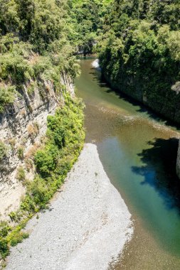 Rangitikei Nehri 'nin turkuaz suyu Yeni Zelanda' nın Manawatu Bölgesi 'ndeki kanyonlarda ve geçitlerde yüksek uçurumlardan ve kaya duvarlarından akıyor.