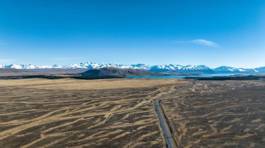 Tekapo Gölü 'ne giden tarımsal bir arazide uzun düz bir yol