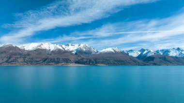 Pukaki Gölü kıyılarının ve arka plandaki kar tepelerinin insansız hava aracı fotoğrafı.