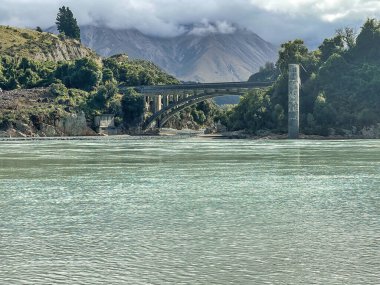 Nehirdeki temiz turkuaz mavi su Rakaia Vadisi 'ndeki köprünün altından akıyor.
