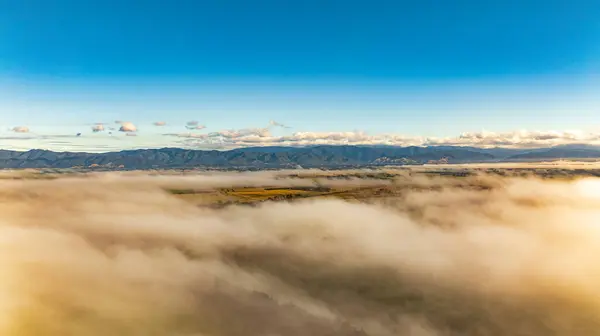 Aerial scene of low cloud in the valley with the mountain range above the clouds