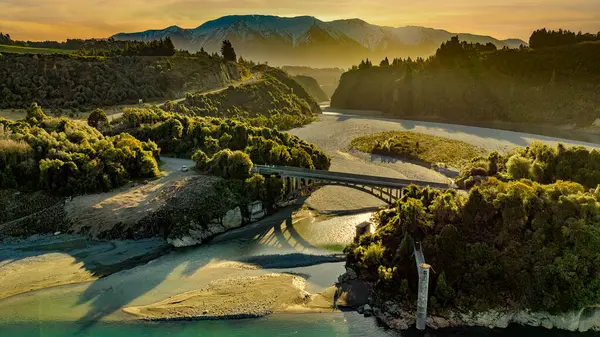 Hava manzarası Rakaia Nehri 'nin mavi suyu geçitten akan kayalara bakan duvarlar yol köprüsünün altında.