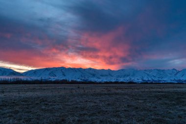 Vibrant sunset over the snow covered mountain range near Twizel clipart