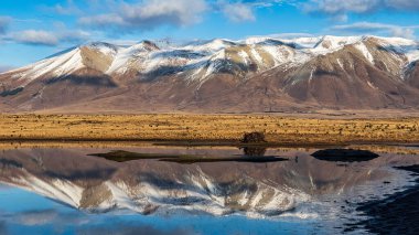 Kırsal ve ücra bir kırsal ve uzak bir ülkenin su kuyusu üzerinde yansımalar var. Kurak tundra çölünde, karlı dağların yakınında.
