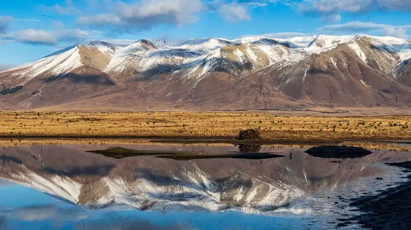 Kırsal ve ücra bir kırsal ve uzak bir ülkenin su kuyusu üzerinde yansımalar var. Kurak tundra çölünde, karlı dağların yakınında.