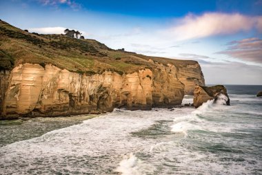 St Clair Dunedin 'in güneyinde yer alan tünel plajında, deniz kenarından oyulmuş kumtaşı kayalıkları, kaya kemerleri ve mağaralar var.