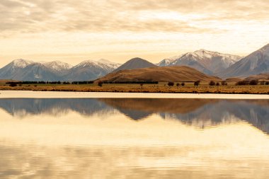 Ashburton dağlarının insansız hava aracı manzarası Heron Gölü 'ne giden kuru arazide bir nehir ve bir göl.
