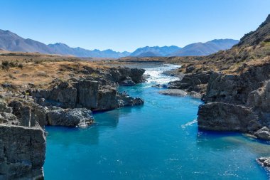 Dağ sıralarıyla çevrili Canterbury NZ 'deki Ahuriri koruma vadisindeki aşırı kurak tarlalar.
