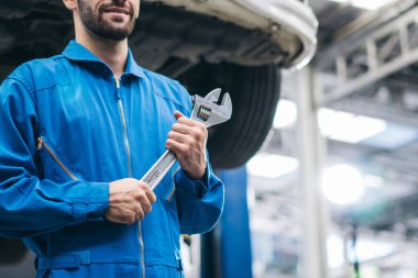 Tamirhanede İngiliz anahtarı aletini tutan tamirci. Aracın hasarını kontrol ediyor, araç tamir ediyor. Hizmetten sonra motor teknisyeni bakımı, alanı kopyala