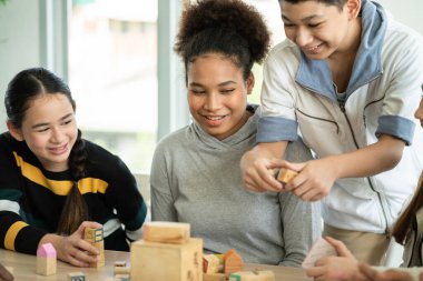 Group of students playing wooden block on the table in the classroom together