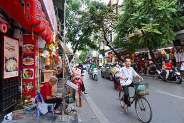 Hanoi, Vietnam - 14 Aralık 2023: Dükkanlar ve sokak satıcıları, Hanoi, Vietnam 'ın işlek caddelerinde bisiklet ve motosikletçilerle birlikte mallarını satıyorlar..