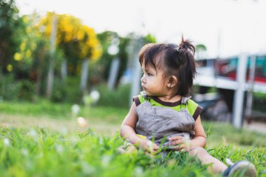 Çocuk akşamları çimlerin üzerinde oturuyor.