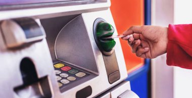 ATM kartı tutan kadın ATM 'den para çekiyor.