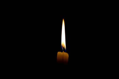 white burning candle on a black background with a long flame