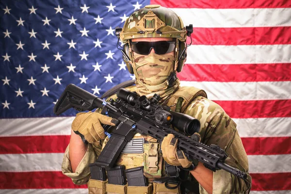 武装特殊部隊の兵士は 背景にアメリカ国旗を掲揚する弾薬を身に着けた機関銃を保持している 迷彩服の陸軍兵士 米国の国旗を背景に — ストック写真