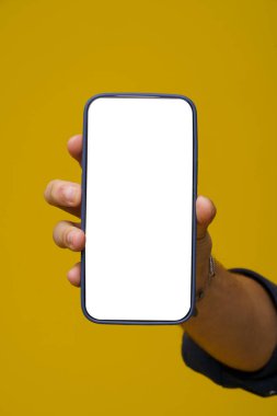 Beyaz ekranlı cep telefonuyla el ele tutuşup geniş bir kopya alanı sunan bir adam. Sarı arka planda izole edilmiş. El ele tutuşmaya odaklanmak teknoloji ve iletişim yönüne dikkat çeker. - Evet. Yüksek