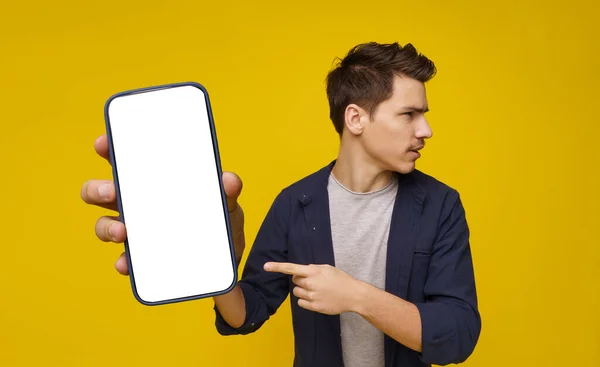 Młody Student Patrząc Bok Wskazując Palcem Telefon Białym Ekranem Obraz — Zdjęcie stockowe