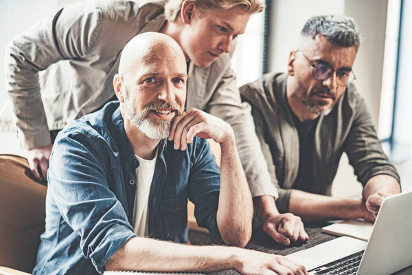 Корпоративная команда из трех человек в современном офисе на чердаке. Изображение выражает профессионализм и подчеркивает разнообразие талантов и опыта членов команды. - Да. Высокое качество фото