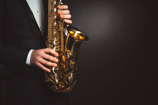 skilled hands of men play saxophone, capturing essence of musical expression and talent. close-up shot against black background. High quality photo