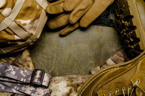 在卡其布的钢制桌子上整齐地摆放着一副军用手套和一条腰带 形成了一个简单而引人注目的军用装备形象 — 图库照片