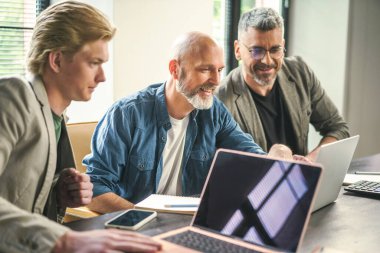 Üç iş adamı bir masada oturmuş dizüstü bilgisayardaki verilere bakarken bir tartışmaya giriştiler..