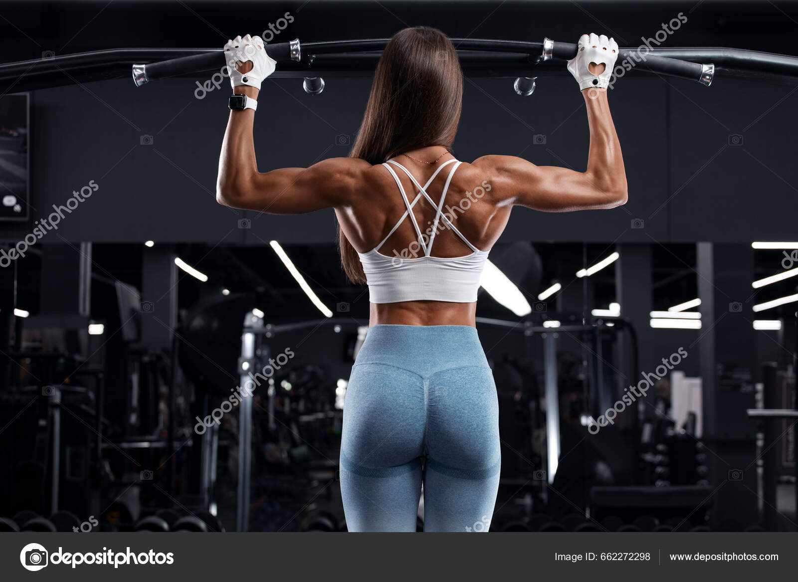 Muscular woman in gym showing back muscles. Strong fitness girl