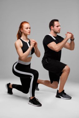 Spor yapan çift hamleler yapıyor. Kaslı adam ve kadın kaslarını gösteriyor.