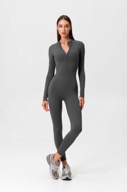 Tulum giymiş bir fitness kadını. Gri arka plandaki atletik kız