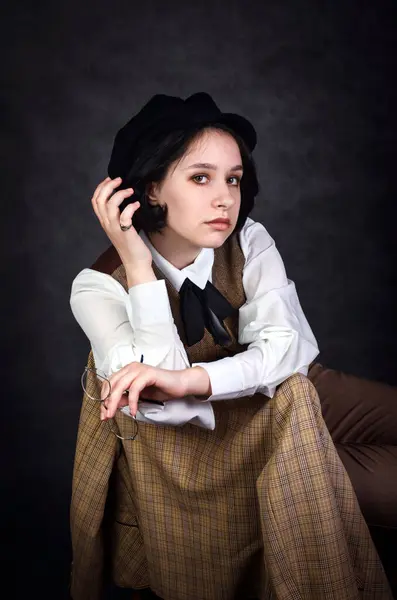 Sherlock Holmes modelinden esinlenerek geleneksel erkek giyimli genç bir kadının etkileyici portresi. Sinema atmosferi için eski ekoseli ve koyu arkaplanlı stil..