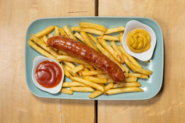 Grilled sausages served with french fries with dips on a plate