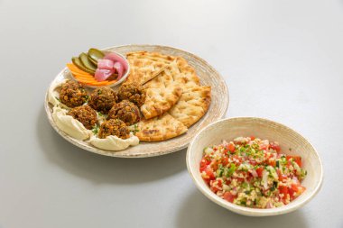 Falafel, ekmek ve sebzeyle servis edilir.