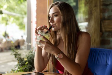 Güzel genç bayan kokteyl içiyor.