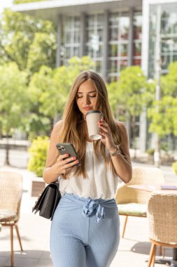 Sokakta yürürken akıllı telefondan konuşan güzel genç bir kadın.