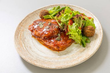 Falafel, ekmek ve sebzeyle servis edilir.