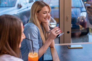 Restoranda şarap içen mutlu kız arkadaşlar.