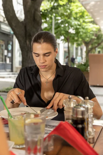 屋外のレストランで一人で食べる若い男 — ストック写真