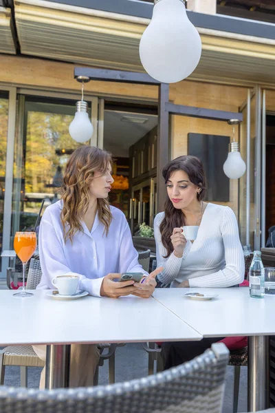 Girlfriends using smartphone in a cafe bar