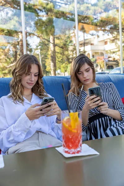 Phone internet addiction, group of girlfriends sitting in the cocktail bar without real communication