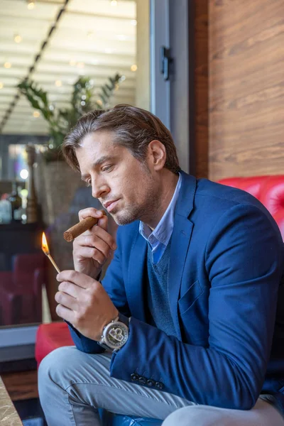 Man lighting cigar with a match