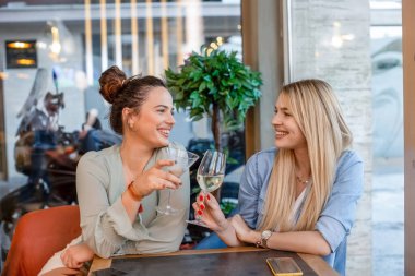 Restoranda şarap içen mutlu kız arkadaşlar.