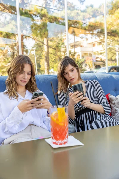 電話のインターネット中毒 本当のコミュニケーションなしにカクテルバーに座っているガールフレンドのグループ — ストック写真