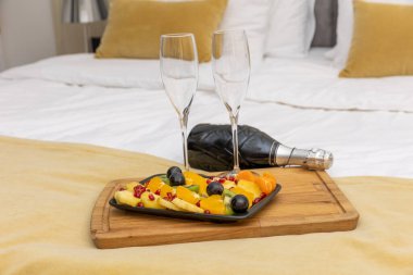 Meyve salatası, şampanya ve bardaklar otel yatağında