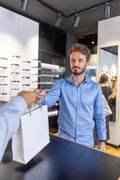 Man buying glasses in eyewear store