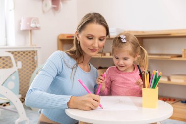 Anne yeni yürümeye başlayan çocuğuyla resim çizer.