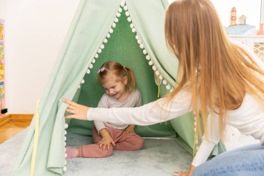 Anne ve kızı çadırda oynuyorlar.