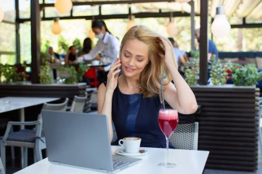 Çekici bir iş kadını, ara veriyor, restoranda akıllı telefondan konuşuyor.