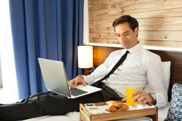 Businessman having breakfast in a hotel bed