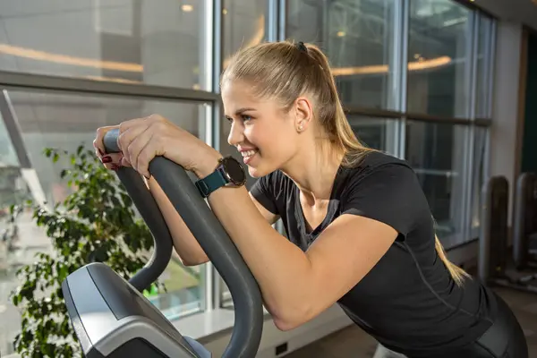 Handsome woman exercising on step machine in modern gym