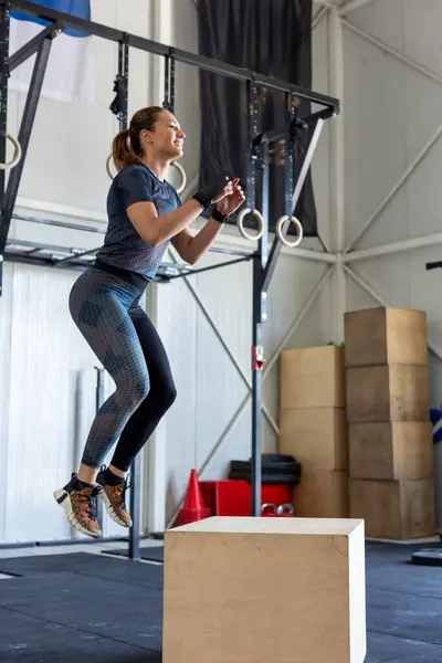 Fitness woman doing box jump workout at cross fit gym